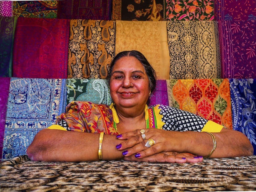A boutique owner smiling in front of colourful fabrics