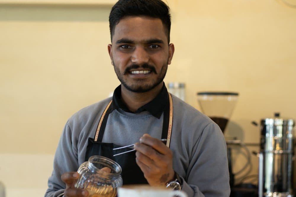 A café owner in an apron smiling at the counter